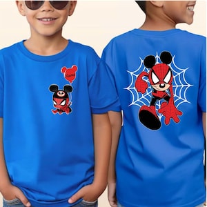 May include: A bright blue t-shirt featuring a small graphic on the front left chest of a character wearing a spider-themed mask and holding a red balloon with the text Name, and a large graphic on the back of the same character in a web design.