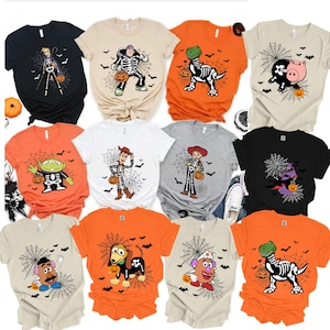 May include: A collection of eleven short-sleeve t-shirts in black, orange, white, gray, and beige, each featuring a screen-printed graphic of a cartoon character wearing a skeleton costume, holding a pumpkin, and standing in front of a spider web.