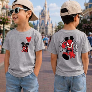 May include: A heather gray t-shirt featuring a small graphic on the front left chest of a cartoon character wearing a spider mask with Mickey Mouse ears and a red balloon with the text Name, and a large back graphic of the same character on a web.