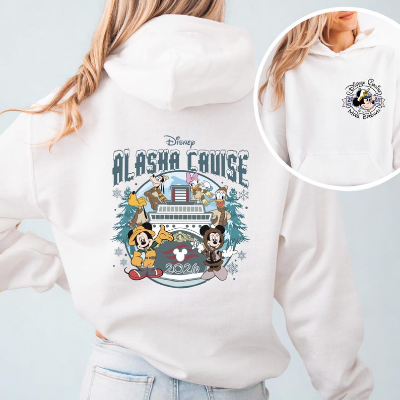 Op de afbeelding: Witte hoodie met een Disney Alaska Cruise-ontwerp. Het ontwerp bevat Mickey Mouse, Minnie Mouse, Donald Duck en Goofy. Het jaar 2026 wordt ook weergegeven. Een kleiner Disney Cruise-ontwerp staat op de voorkant.