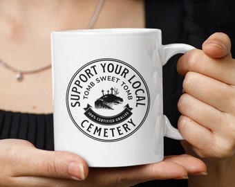 Taza de Halloween con el mensaje "Apoya a tu cementerio local", taza con humor negro, regalo para el director de la funeraria, taza del cementerio, taza de la temporada espeluznante, taza gótica, taza de café de 11 oz
