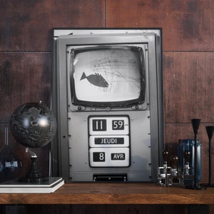May include: A vintage-style television with a black and white image of a fish on the screen. The television has a digital clock that reads "11 59" and a date display that reads "JEUDI 8 AVR".