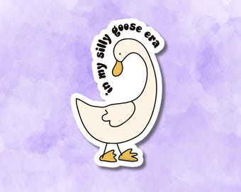 May include: A sticker featuring a cartoon goose with the text "in my silly goose era". The goose is white with yellow beak and feet, outlined in black. The background is a soft purple.