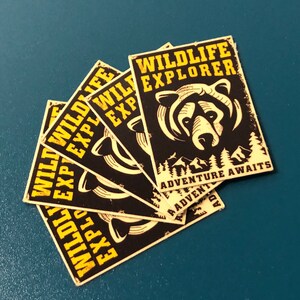May include: Five black and yellow stickers with the text "WILDLIFE EXPLORER" and a bear illustration. The text "ADVENTURE AWAITS" is on the bottom of the sticker.
