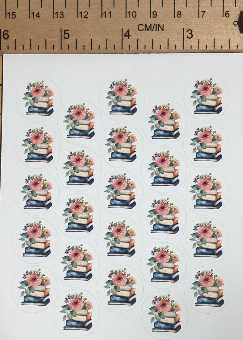 May include: A sheet of round stickers featuring watercolor illustrations. Each sticker shows a stack of books topped with a bouquet of pink and yellow flowers. The stickers are arranged in a grid pattern.