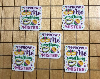 Puede incluir: Cinco pegatinas cuadradas blancas con un tema de Mardi Gras en morado, verde y amarillo. Las pegatinas dicen "Throw Me Something Mister".