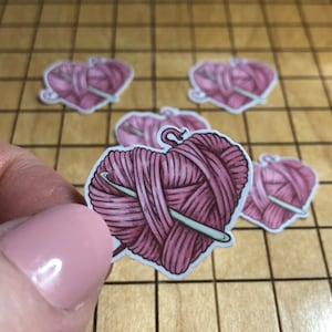 May include: Five pink heart-shaped stickers with a pink yarn ball and a knitting needle inside each heart.