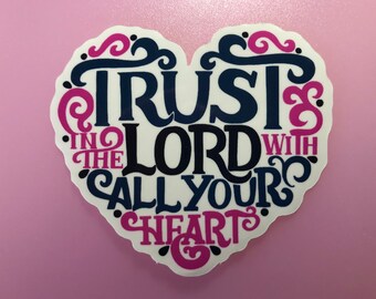 Puede incluir: Una pegatina en forma de corazón con el texto "Trust in the Lord with all your heart" en un esquema de color azul marino y rosa.