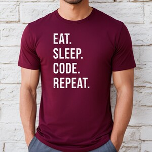 May include: A maroon t-shirt with white text that reads "EAT. SLEEP. CODE. REPEAT."