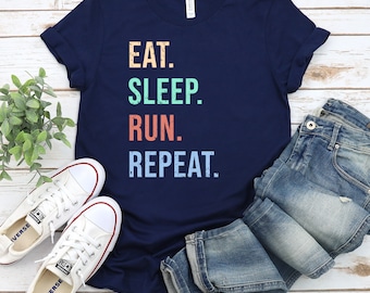 May include: A navy blue t-shirt with the text "EAT. SLEEP. RUN. REPEAT." in a vintage style font. The text is in different colors: yellow, blue, orange, and light blue.