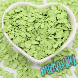 May include: A heart-shaped white bowl filled with light green leaf-shaped polymer clay pieces. Each leaf has a white vein design. The word "MIMAXXY" is written in a teal, cursive font across the bottom right.