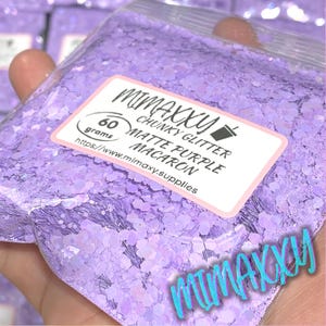 May include: A resealable bag of 60 grams of chunky matte purple glitter called "Matte Purple Macaron" by MiMaxy. The bag has a label with the company's name and website: https://www.mimaxy.supplies