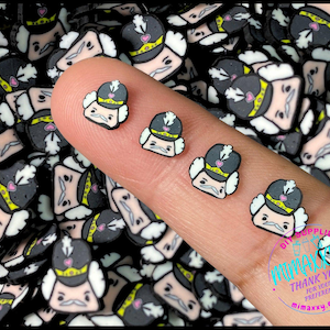 May include: A close-up of a hand holding a variety of small, colorful, resin figurines. The figurines are all of the same design, depicting a cartoon character with a white face, black hair, and a red hat. The figurines are scattered across the hand and the background, creating a colorful and whimsical scene.