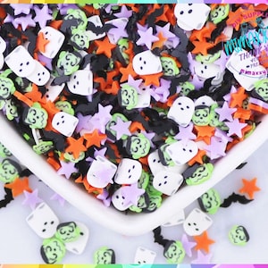 May include: A bowl filled with colorful Halloween-themed sprinkles. The sprinkles are shaped like ghosts, bats, stars, and pumpkins. The sprinkles are in various colors, including white, black, orange, green, and purple.
