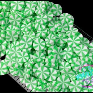 May include: A large pile of green and white peppermint candy sprinkles. The sprinkles are in the shape of a candy disc with a swirl design.
