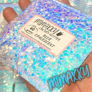 May include: A close-up of a bag of blue iridescent chunky glitter. The bag is labeled "MIMAKKU CHUNKY GLITTER BLUE OPALESCENT" and "60 grams".
