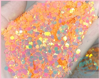 May include: Orange and iridescent glitter with a holographic finish. The glitter is loose and appears to be in a hand.