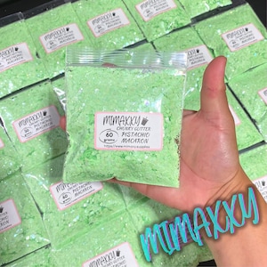 May include: A bag of green chunky glitter labeled "Mimaxxu Chunky Glitter Pistachio Macaron 60 grams" with the website address "https://www.mimary.supplies".