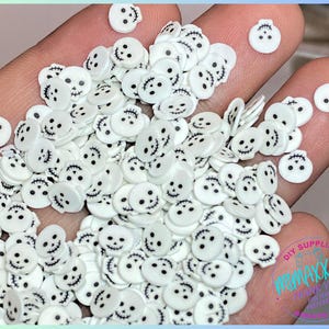 May include: A large quantity of white, flat, plastic Halloween-themed sprinkles with black jack-o'-lantern faces.