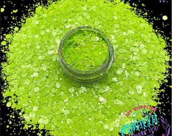 May include: A close-up of a jar of bright green glitter. The glitter is in a clear jar with a black lid. The glitter is very fine and sparkly.