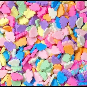 May include: A large assortment of colorful cloud-shaped sprinkles. The sprinkles are in various shades of pink, blue, yellow, green, and purple.