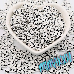 May include: White heart-shaped bowl filled with black and white musical note-shaped polymer clay pieces. The clay pieces are scattered around the bowl. The image has a bright, clean aesthetic.