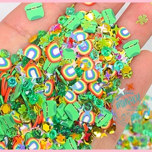 May include: A handful of colorful craft embellishments, including green leprechaun hats, rainbows, shamrocks, stars, and faceted gems. The embellishments are in various sizes and colors, perfect for crafting projects.