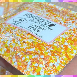May include: A close-up of a bag of orange, yellow, and white chunky glitter labeled "MiniMaxy Chunky Glitter Candy Corn 60 grams https://www.minimaxy-supplies.com".