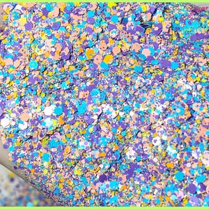 May include: A close-up of a mixture of colorful glitter, including shades of blue, purple, yellow, and pink. The glitter is scattered on a hand, creating a vibrant and sparkly texture.