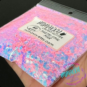 May include: A 60 gram bag of chunky glitter in pastel pink opal. The glitter is iridescent and has a variety of sizes. The bag is labeled with the name of the shop, "mimaxxy.etsy.com".