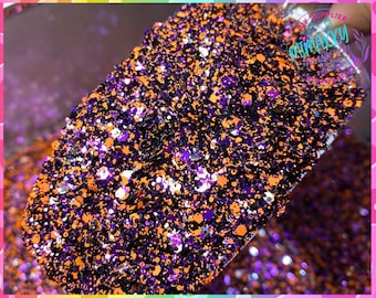 Op de afbeelding: Een close-up van een mengsel van oranje, paarse, zwarte en zilveren glitter. De glitter zit in een doorzichtige container en is klaar om te worden gebruikt voor knutselprojecten.