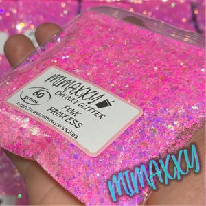 May include: A clear plastic bag filled with bright pink chunky glitter. A white label reads "MIMAXXY CHUNKY GLITTER PINK PRINCESS" with a weight of 60 grams. The glitter is held in a hand.