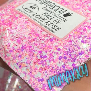 May include: A close-up of pink, white, and purple glitter in a variety of shapes and sizes. The glitter is labeled "Fall in Love Rose" and "Shape Glitter 60 grams".