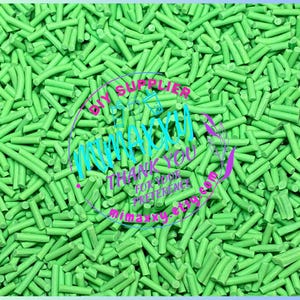 May include: A close-up image of a large quantity of green sprinkles. The sprinkles are long and thin, resembling small sticks.