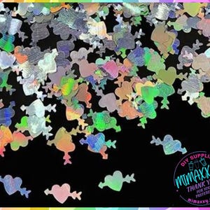 May include: A scattering of iridescent holographic glitter in the shape of hearts with arrows. The glitter is perfect for crafting and adding sparkle to projects.