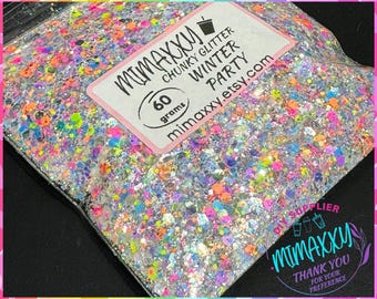 May include: A close-up of a clear plastic bag filled with colorful chunky glitter. The bag has a label that reads "MIMAXXU CHUNKY GLITTER WINTER PARTY" and "60 grams".