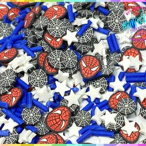 May include: A variety of colorful polymer clay charms featuring a superhero theme. The charms include red and blue spider webs, red and blue stars, and red and blue superhero masks. The charms are perfect for adding a touch of fun to your crafts.