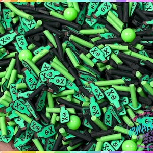 May include: Green and black sprinkles in the shape of bottles with a skull and crossbones design. The sprinkles are perfect for decorating cakes, cupcakes, and other desserts.
