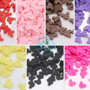 May include: Assortment of colorful Mickey Mouse shaped sprinkles in red, pink, yellow, black, pink, and purple.