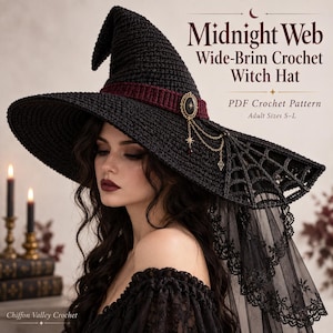 Könnte beinhalten: Ein schwarzer Häkel-Hexenhut mit breiter Krempe, dunkelrotem Band, einer dekorativen ovalen Brosche mit hängenden Goldketten und einem schwarzen Spitzenschleier. Der Text lautet Midnight Web Wide-Brim Crochet Witch Hat PDF Crochet Pattern.