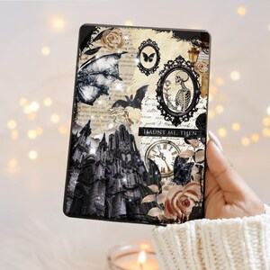 May include: A decorative tablet case featuring a gothic design with a black castle, bats, butterflies, roses, and a skeleton in an oval frame. The case has the text "Haunt Me, Then" and a vintage clock design.