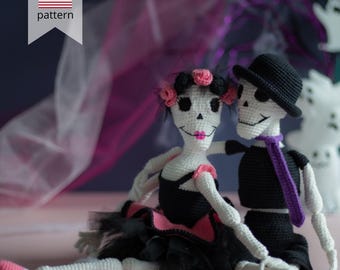May include: Crocheted Day of the Dead couple, a male in a black suit and hat with a purple scarf, and a female in a black and pink dress with a flower crown. The dolls are white with black accents and pink lips. The image includes a "PDF pattern" graphic.