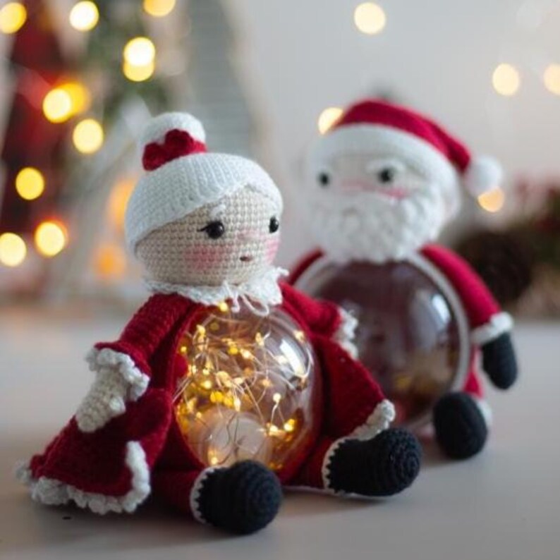 Peut inclure: Deux ornements de No&euml;l au crochet repr&eacute;sentant le P&egrave;re No&euml;l et la M&egrave;re No&euml;l. L'ornement du P&egrave;re No&euml;l a une barbe blanche et un chapeau rouge. L'ornement de la M&egrave;re No&euml;l a un chapeau blanc et une robe rouge. Les deux ornements ont un corps en verre transparent rempli de guirlandes lumineuses.