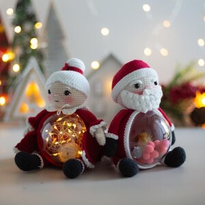 Peut inclure: Figurines au crochet du P&egrave;re No&euml;l et de la M&egrave;re No&euml;l avec des ventres transparents remplis de lumi&egrave;res et de bonbons roses. Les figurines sont v&ecirc;tues de tenues rouges et blanches avec des chaussures noires. D&eacute;corations de No&euml;l festives.