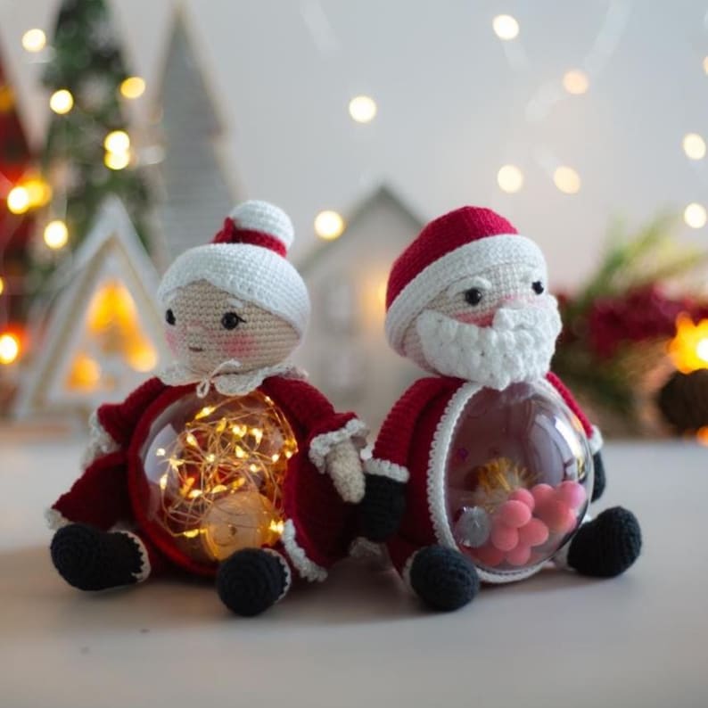 Peut inclure: Figurines au crochet du P&egrave;re No&euml;l et de la M&egrave;re No&euml;l avec des ventres transparents remplis de lumi&egrave;res et de bonbons roses. Les figurines sont v&ecirc;tues de tenues rouges et blanches avec des chaussures noires. D&eacute;corations de No&euml;l festives.