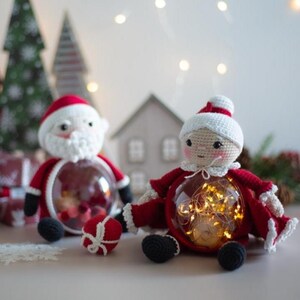 Peut inclure: Deux figurines du P&egrave;re No&euml;l au crochet, une masculine et une f&eacute;minine, avec des ventres transparents. Le P&egrave;re No&euml;l masculin a une barbe blanche et un costume rouge. Le P&egrave;re No&euml;l f&eacute;minin a un chapeau blanc et un costume rouge. Les deux ont des chaussures noires.