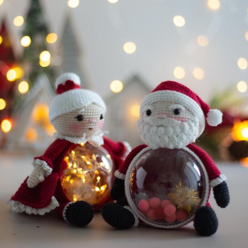Peut inclure: Deux ornements de No&euml;l crochet&eacute;s : un P&egrave;re No&euml;l et une M&egrave;re No&euml;l. Chaque figurine a un corps rond et transparent rempli de lumi&egrave;res ou de petites d&eacute;corations. Ils sont v&ecirc;tus de tenues rouges et blanches, avec des chaussures noires.