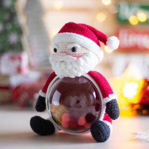 Peut inclure: Une figurine du P&egrave;re No&euml;l au crochet, avec un chapeau, un manteau rouges et des bottes noires. La figurine du P&egrave;re No&euml;l a une barbe blanche et un corps rond et transparent rempli de petits objets color&eacute;s. Une d&eacute;coration de vacances festive.