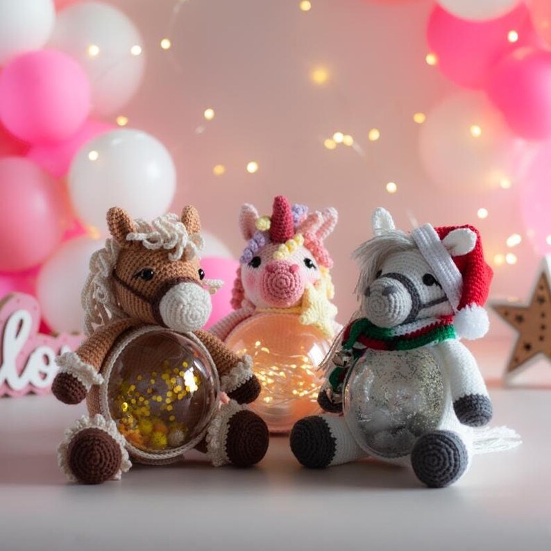 May include: Three handmade crochet horse and unicorn figures. The brown horse has a clear belly filled with yellow confetti. The unicorn has a pink body and colorful mane. The white horse wears a Santa hat and a green and red scarf.