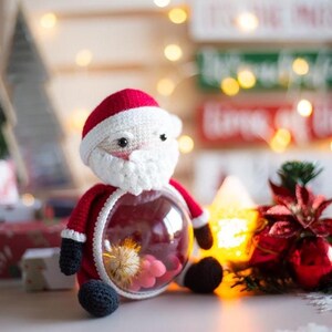Peut inclure: Ornement de No&euml;l fait &agrave; la main en forme de P&egrave;re No&euml;l. La figurine rouge et blanche au crochet a un ventre rond et transparent rempli de fleurs s&eacute;ch&eacute;es. L'ornement a des pieds noirs et une barbe blanche.